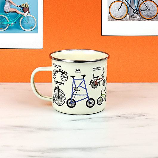 bike enameled mug set on a desk with an orange background.