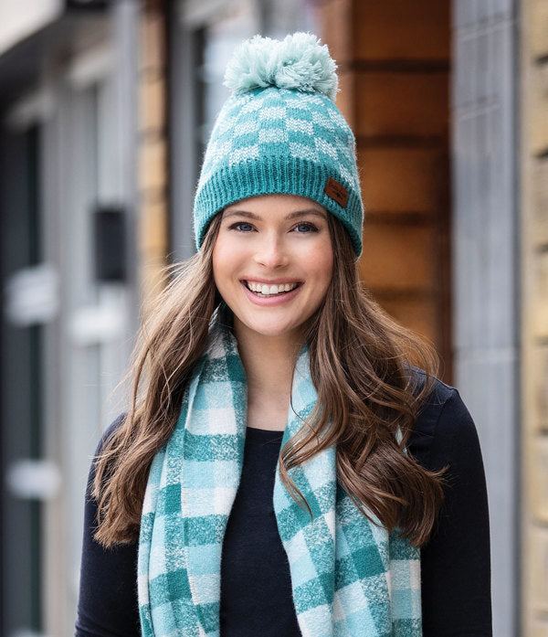 a woman modeling the teal Sweater Weather Pom Hat while standing outside