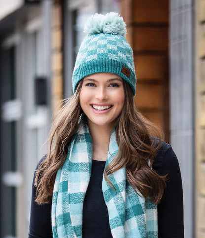 a woman modeling the teal Sweater Weather Pom Hat while standing outside