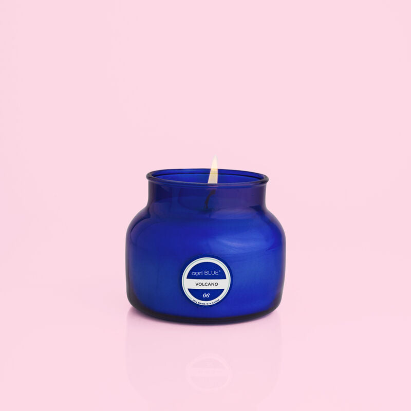 Volcano Signature Blue Petite Jar Candle lit on a light pink background.