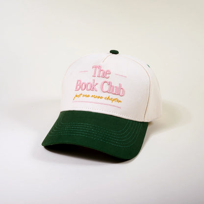 White and green cap with 'The Book Club' text in pink and just one more chapter text in yellow shown on a white background