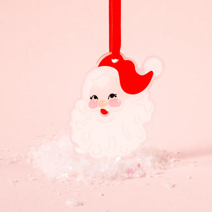 acrylic santa face ornament set with artificial snow on a light pink background