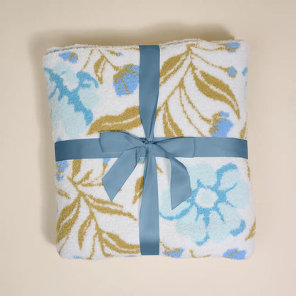 Folded blanket with floral pattern and blue ribbon on a beige background