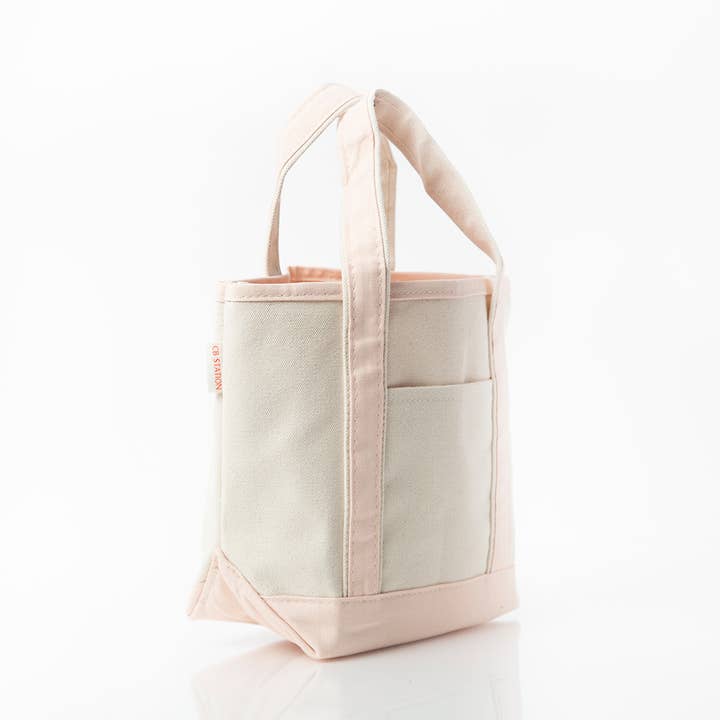 angled view of off white tote with pale pink handles and trim