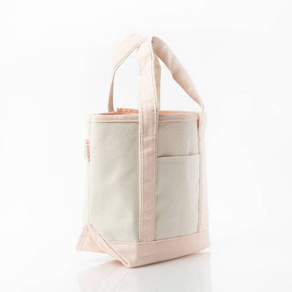 angled view of off white tote with pale pink handles and trim