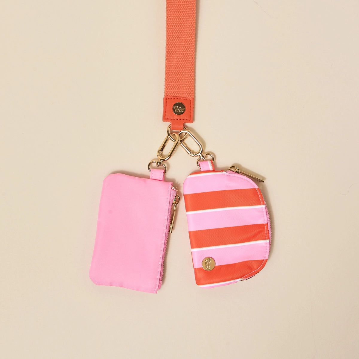 Pink and orange striped pouches with a matching strap on a beige background