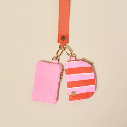 Pink and orange striped pouches with a matching strap on a beige background