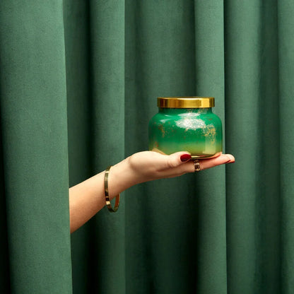 hand holding crystal pine candle in front of a green curtain.