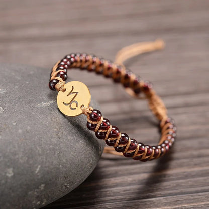 capricorn bracelet draped on a stone on a wooden table.