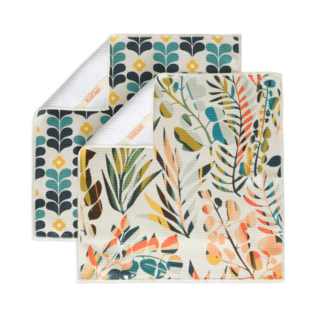 Two styles of colorful leaves. All purpose towels on a white background with their corners flapped over, showing hanging loop.