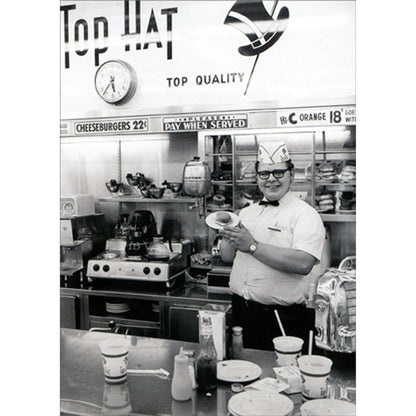front of card is a man holding a hamburger on a plate inside of a diner in black and white