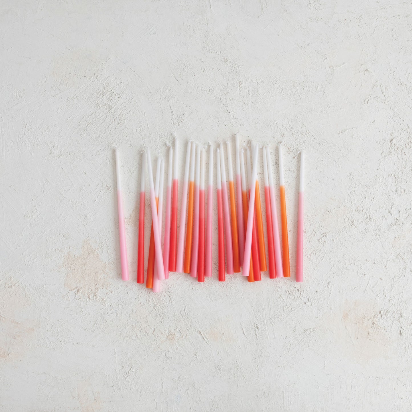 thin taper candles that ombre from withe to pink or white to orange on a textured background