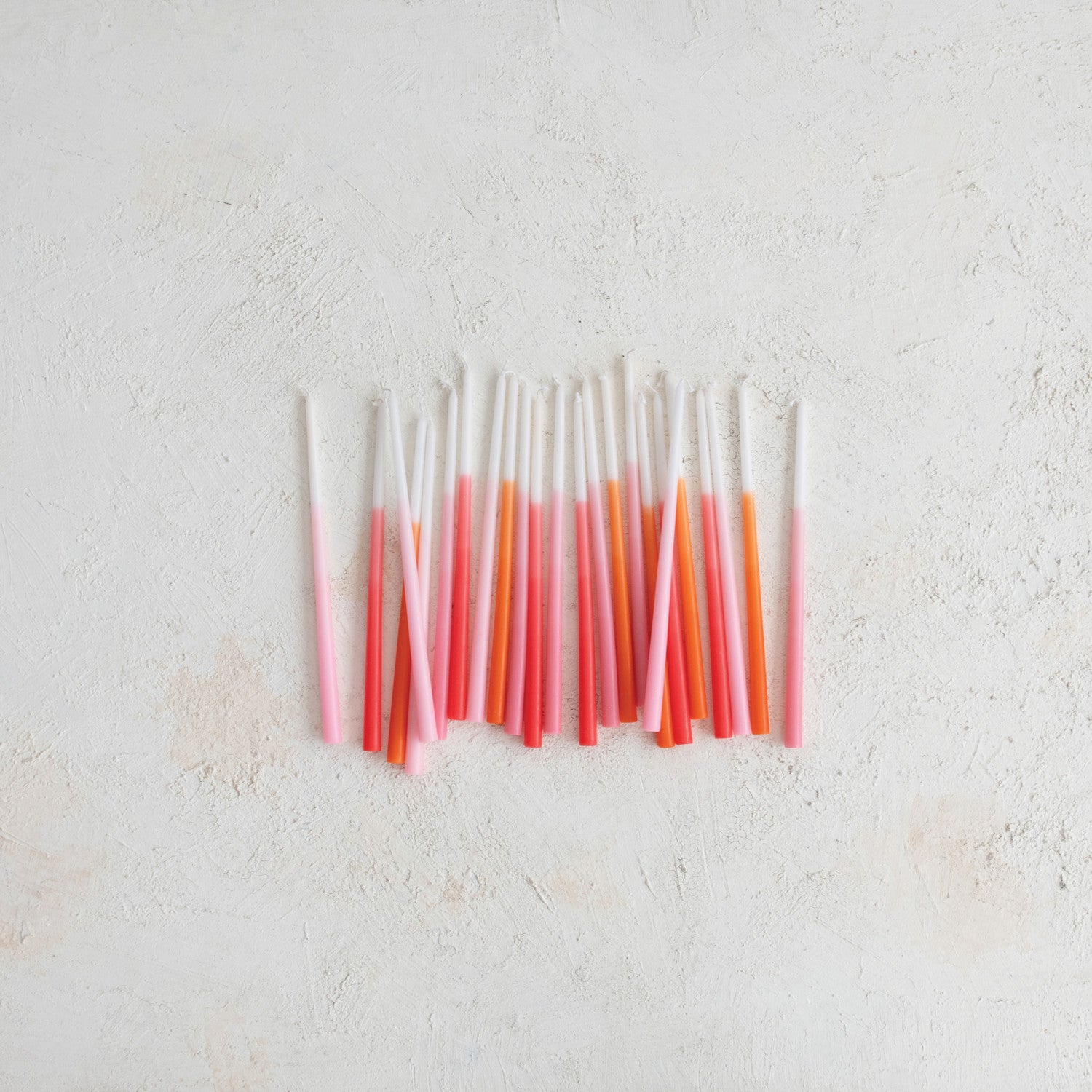 thin taper candles that ombre from withe to pink or white to orange on a textured background