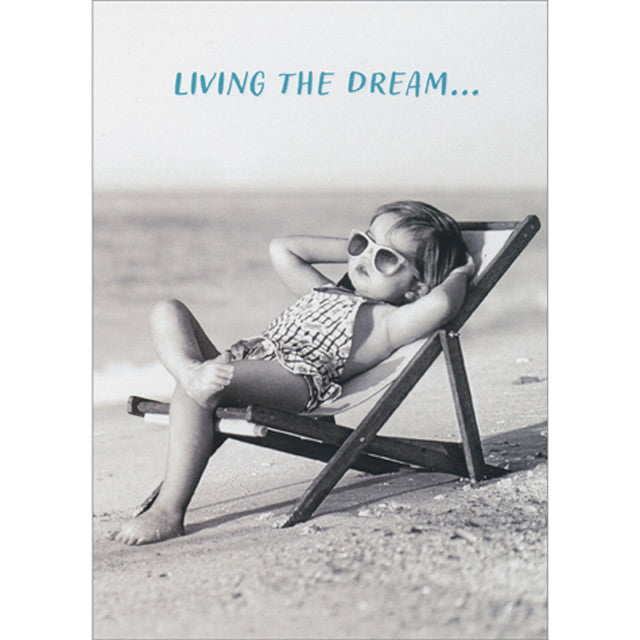 front of card is a little girl laying in a lounge chair on a beach