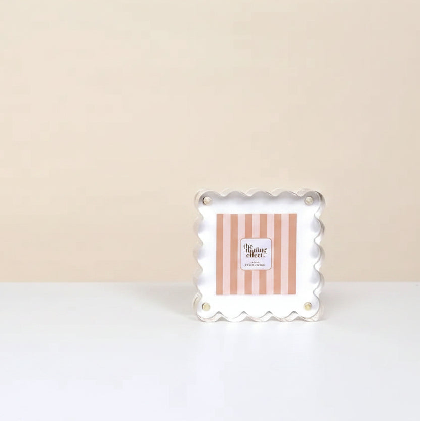 white acrylic frame with center card branded with 'the darling effect' set on a white surface in front of a beige background