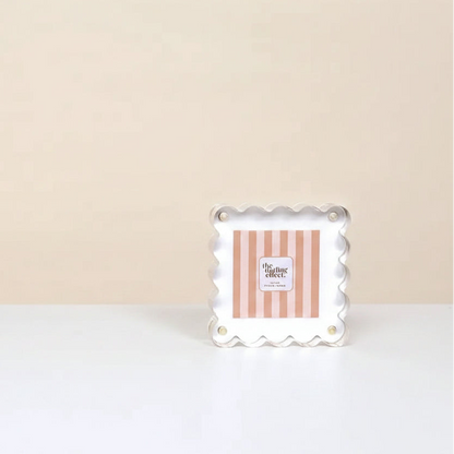 white acrylic frame with center card branded with 'the darling effect' set on a white surface in front of a beige background