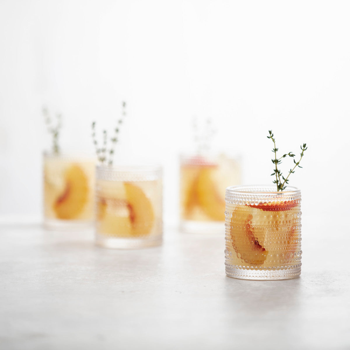 4 clear jupiter double old fashion glasses filled with beverage and garnished with fruit. 