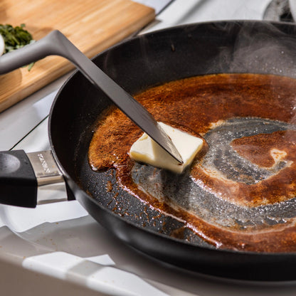 Butter being added to a hot frying pan on a stove