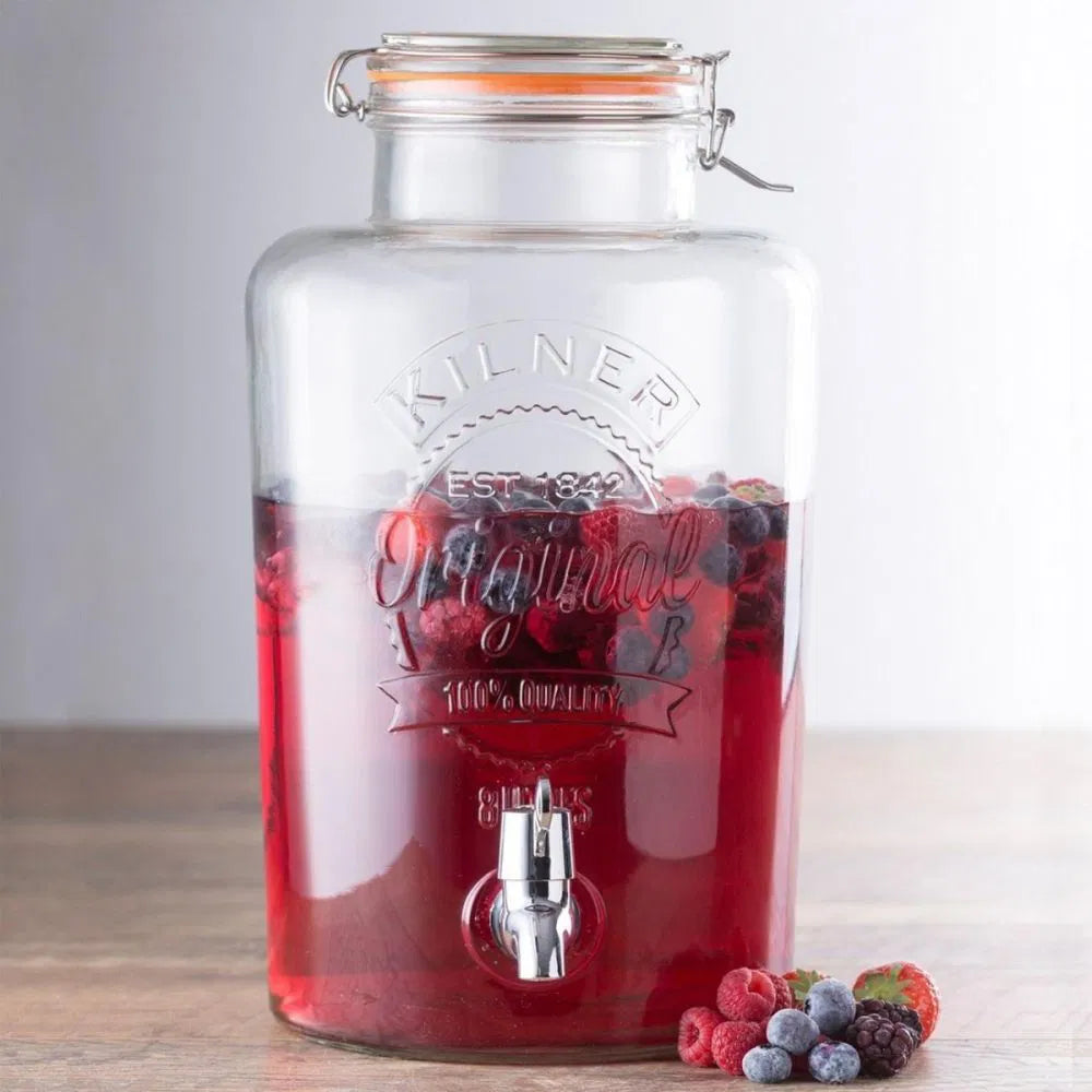 round glass drink dispenser filled with beverage and berries.