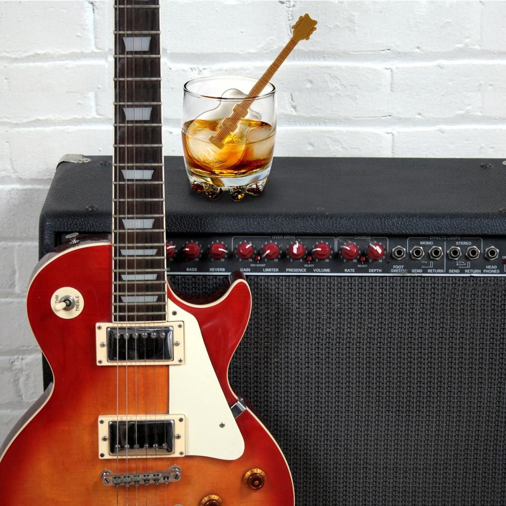 beverage with guitar shaped ice stirred in it set on an amp with a guitar next to it.