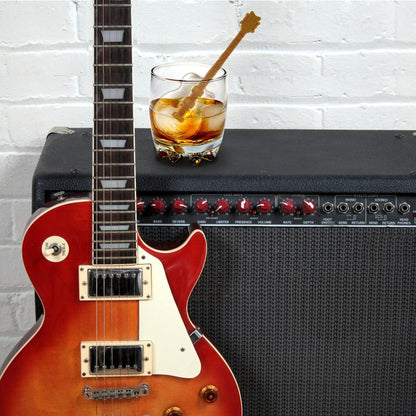 beverage with guitar shaped ice stirred in it set on an amp with a guitar next to it.