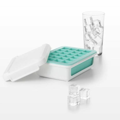 ice cube tray with ice cube set around it and a glass behind it