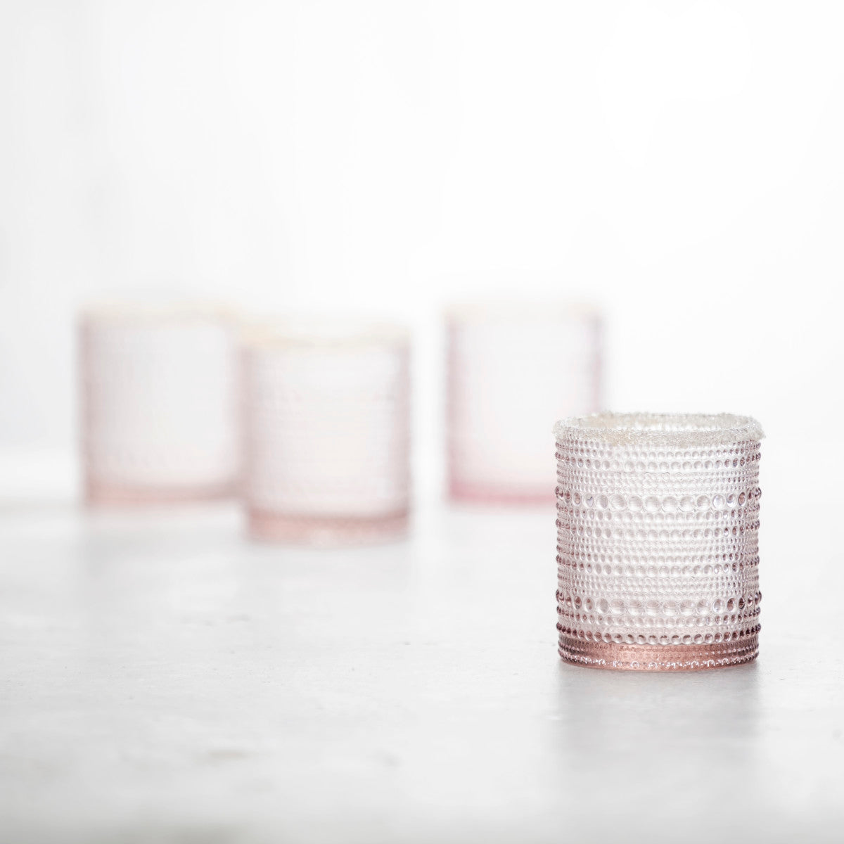 4 pink jupiter double old fashion glasses arranged on a countertop.