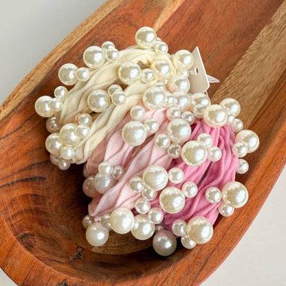6 pink and cream hair ties with pearls on them in a wood bowl