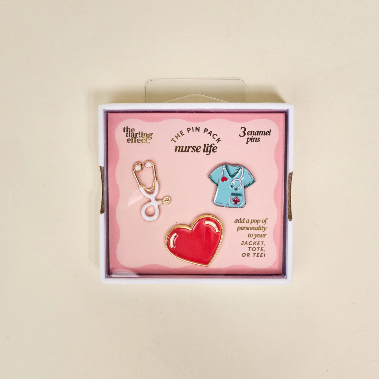 Set of three nurse-themed enamel pins in a decorative box on a beige background