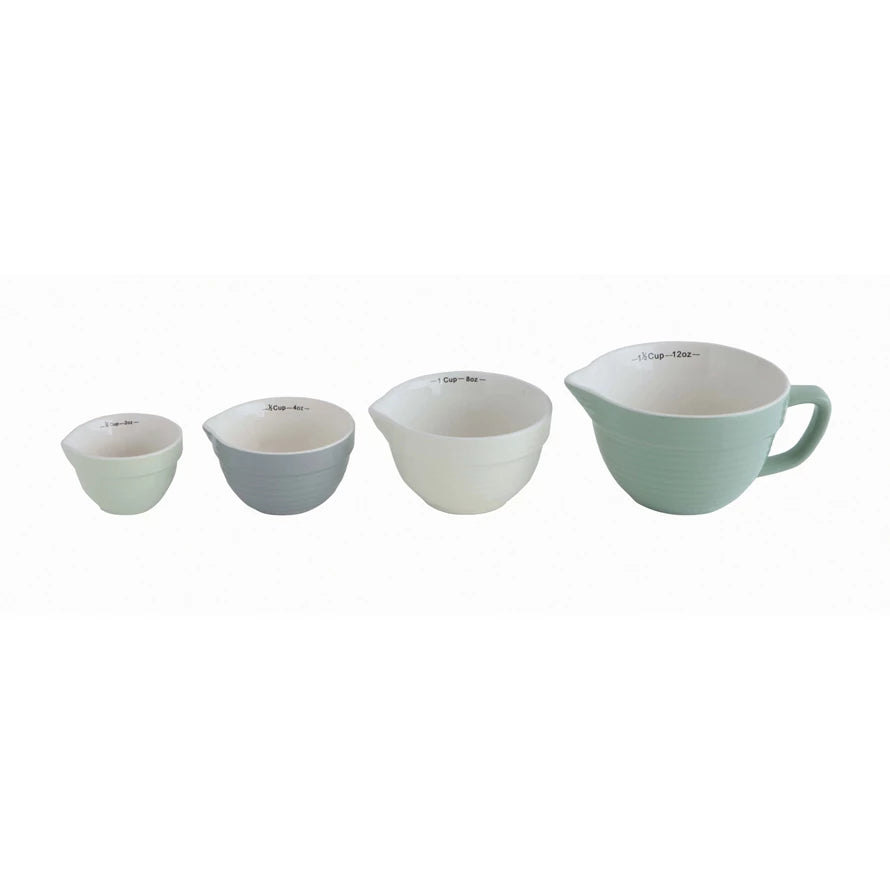 4 batter bowl shaped measuring cups in a row on a white background.
