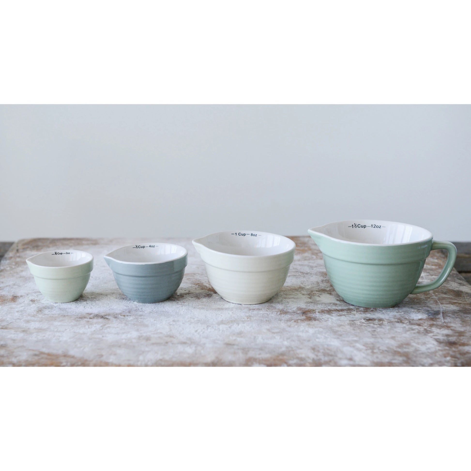 4 batter bowl shaped measuring cups in a row on a countertop dusted with flour.