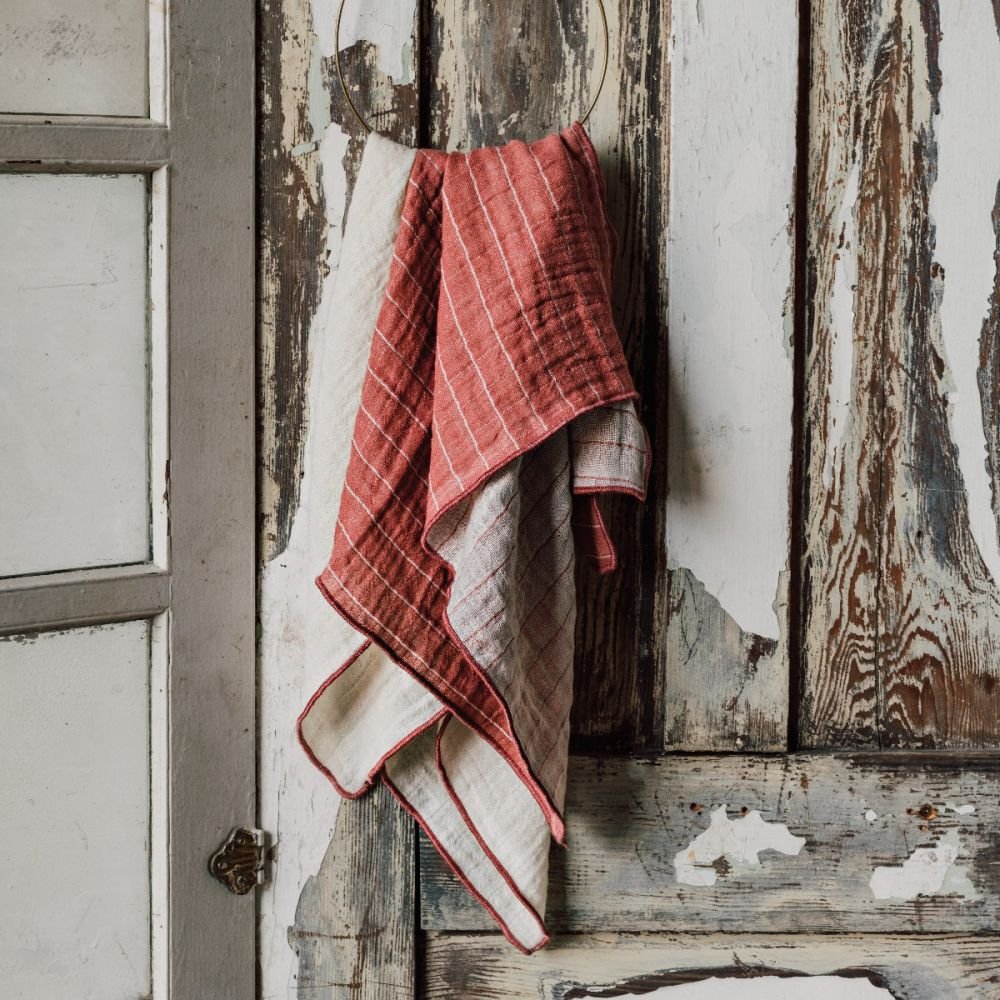 both colors of canyon rose towels draped over a loop hanging on wood slat wall.