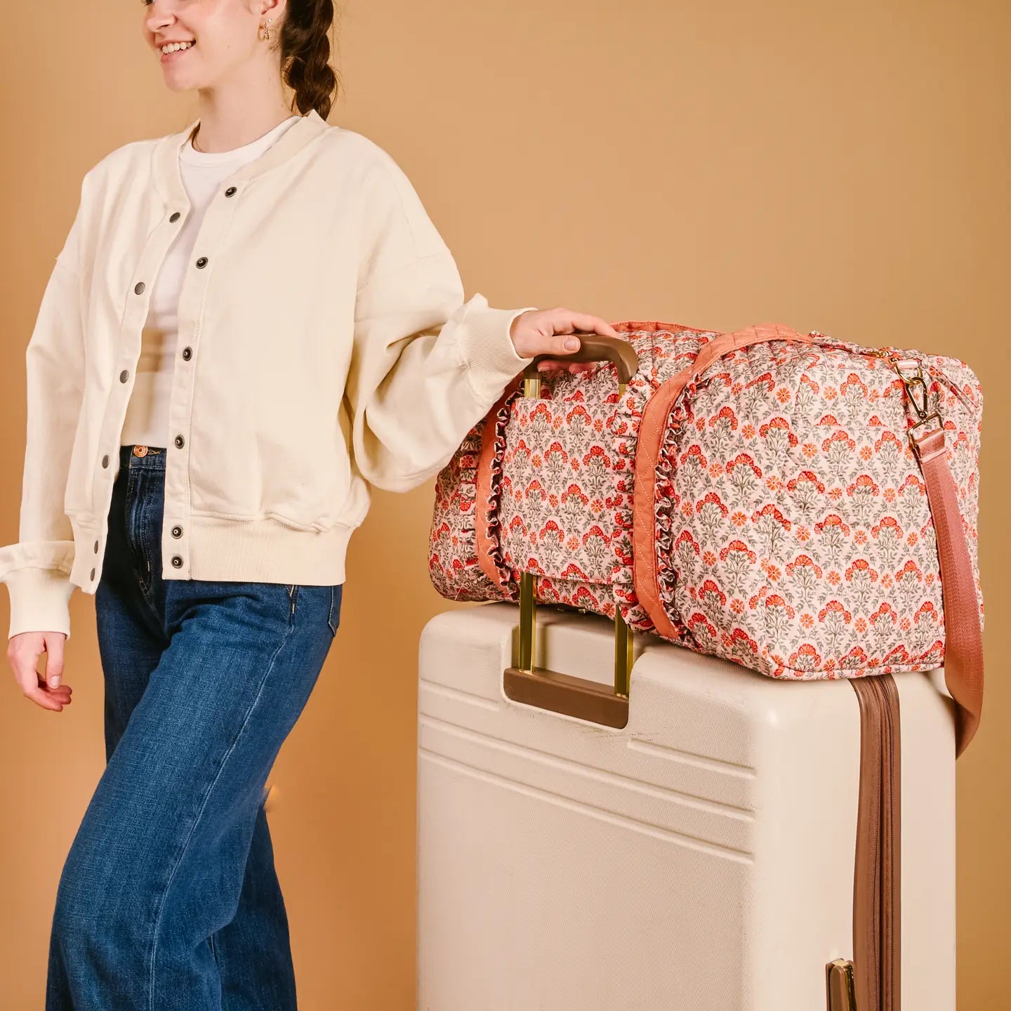 person with Everbloom Dusty Rose weekender bag slid over the handle of a suitcase