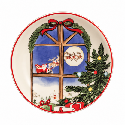 A round ceramic Christmas small plate featuring a festive window scene with Santa Claus in a sleigh, a decorated Christmas tree, wrapped gifts, and a red bow on a white background.