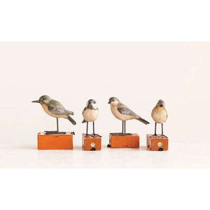 Four bird figurines on small orange boxes shown on a light background