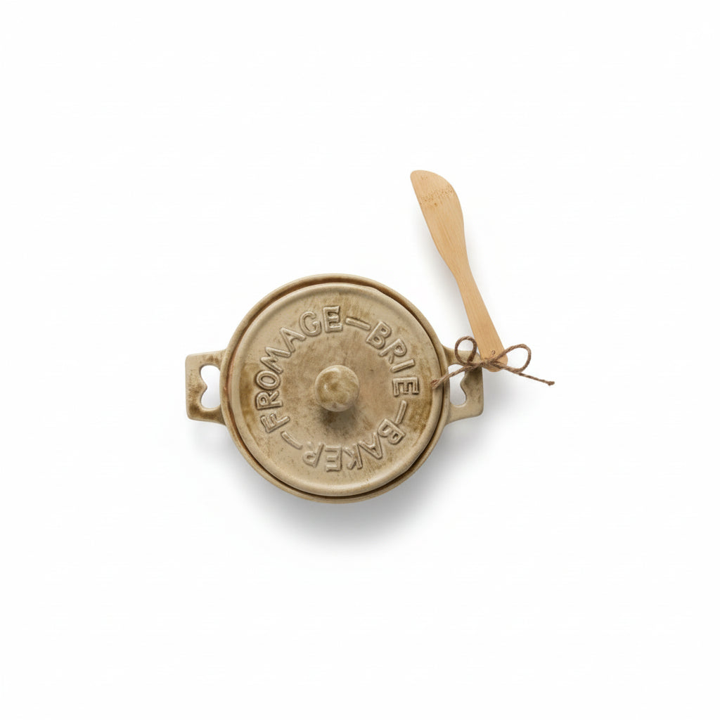 top view of brie baker with a light beige glaze and wooden spreader