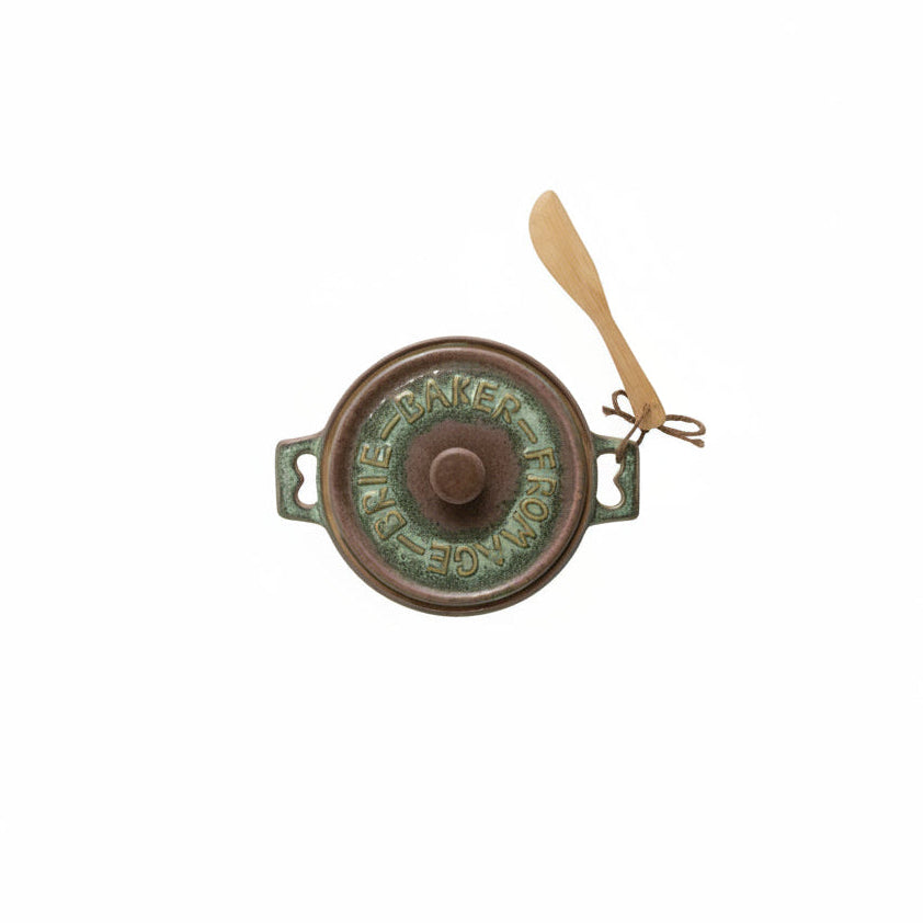 top view of brie baker with a deep brown and green glaze and wooden spreader