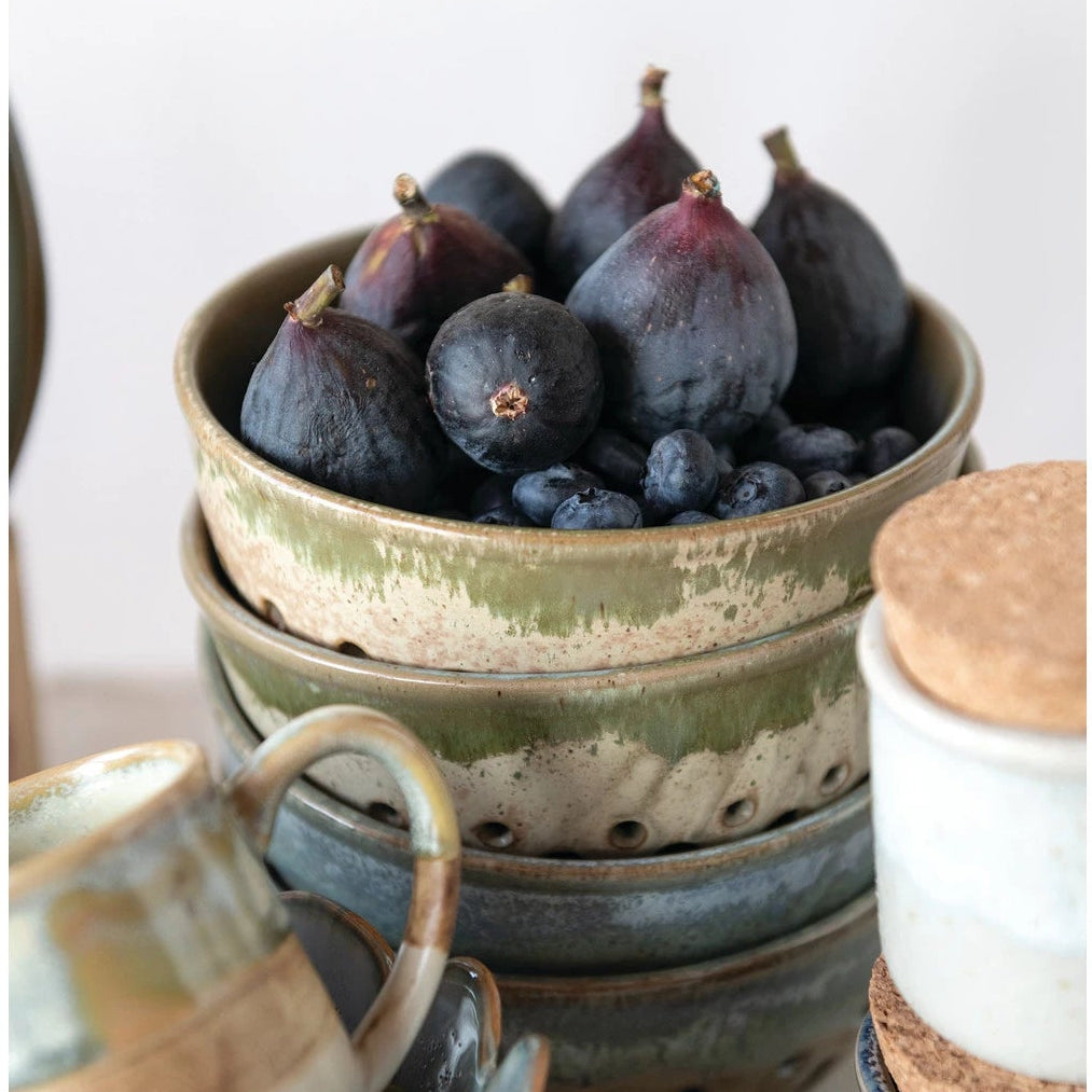 Stack of ceramic bowls filled with figs and blueberries on a neutral background