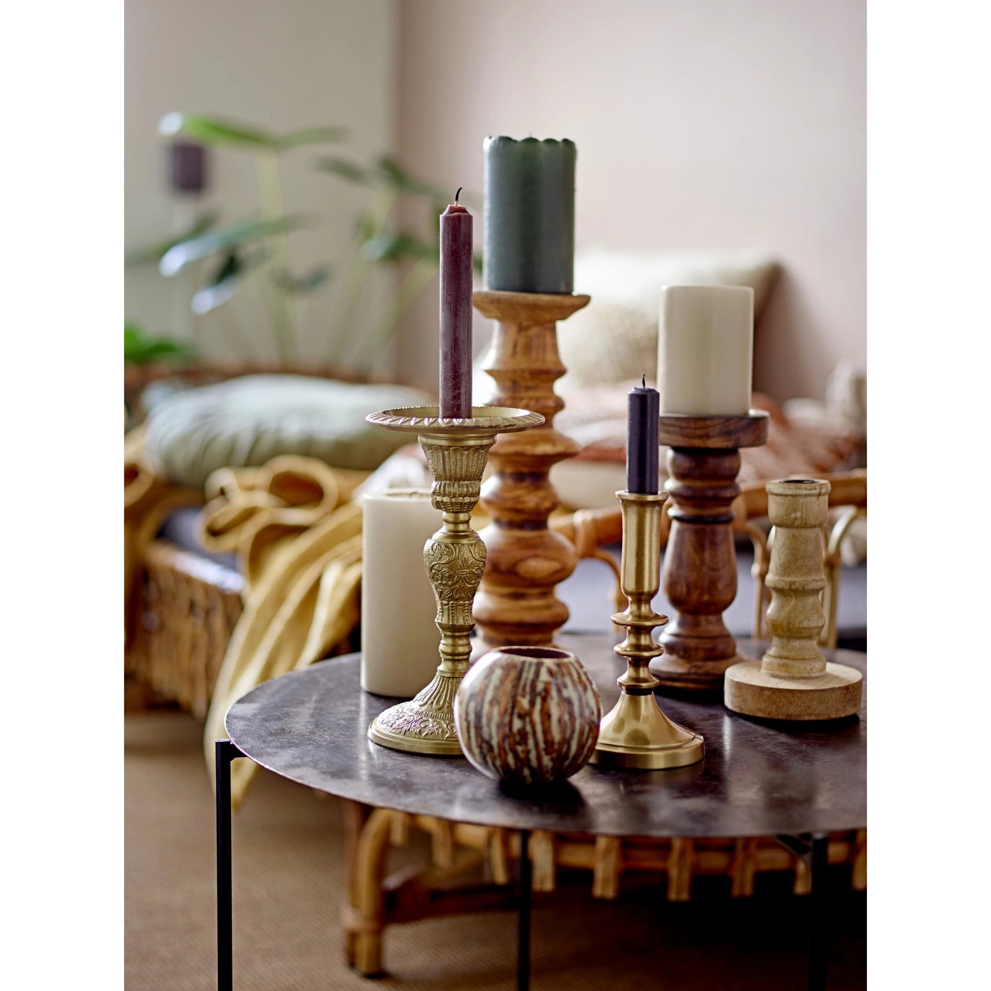 assortment of candle holders arranged on a side table with a couch in the background.