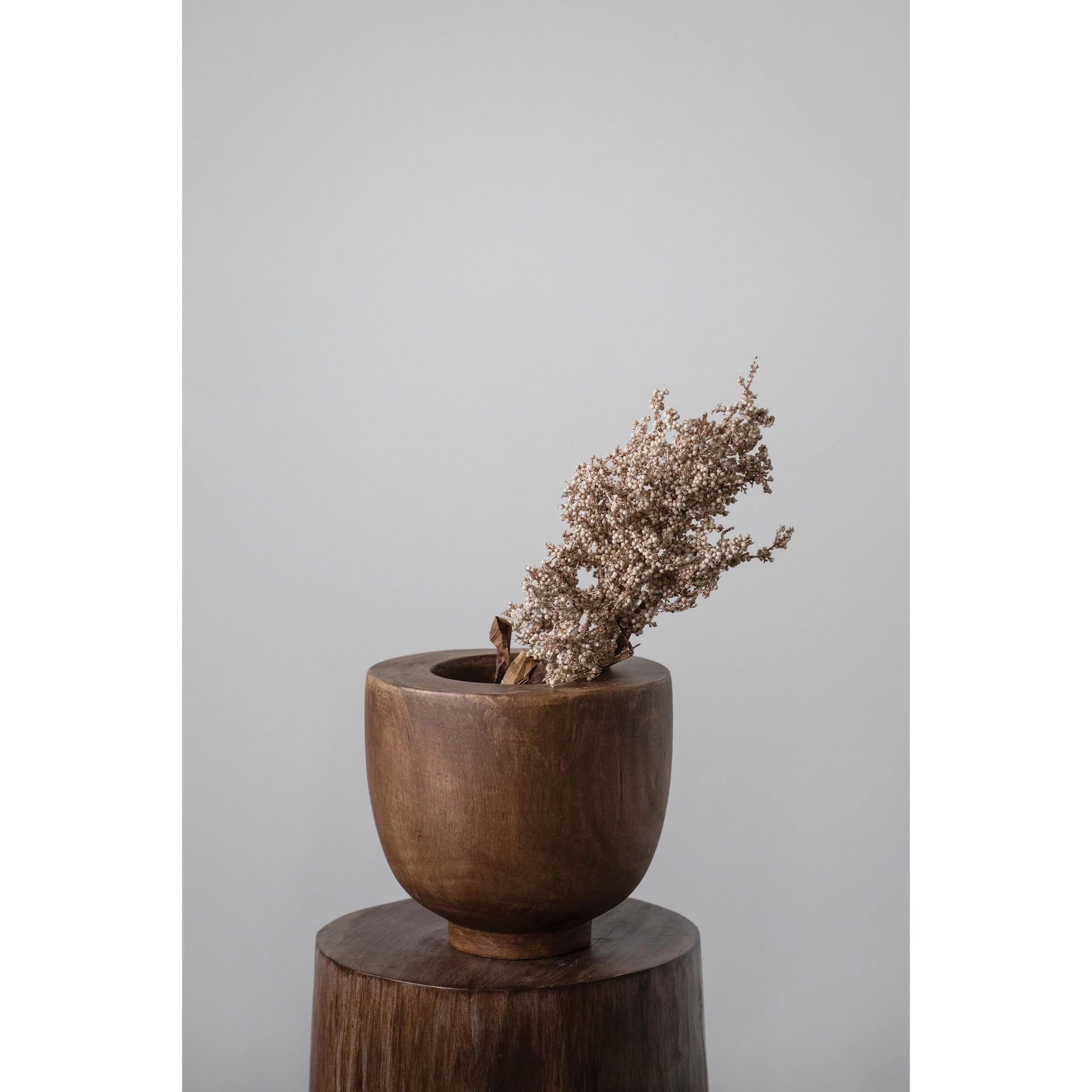 wood bowl filled with dried botanicals set on a wooden table.
