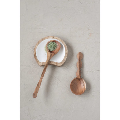 top view of 2 wooden spoons, one set in a small white dish, on a grey table.