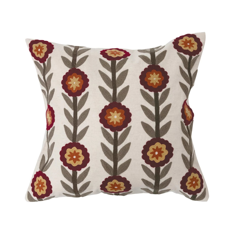 cream pillow with embroidered floral design on a white background.