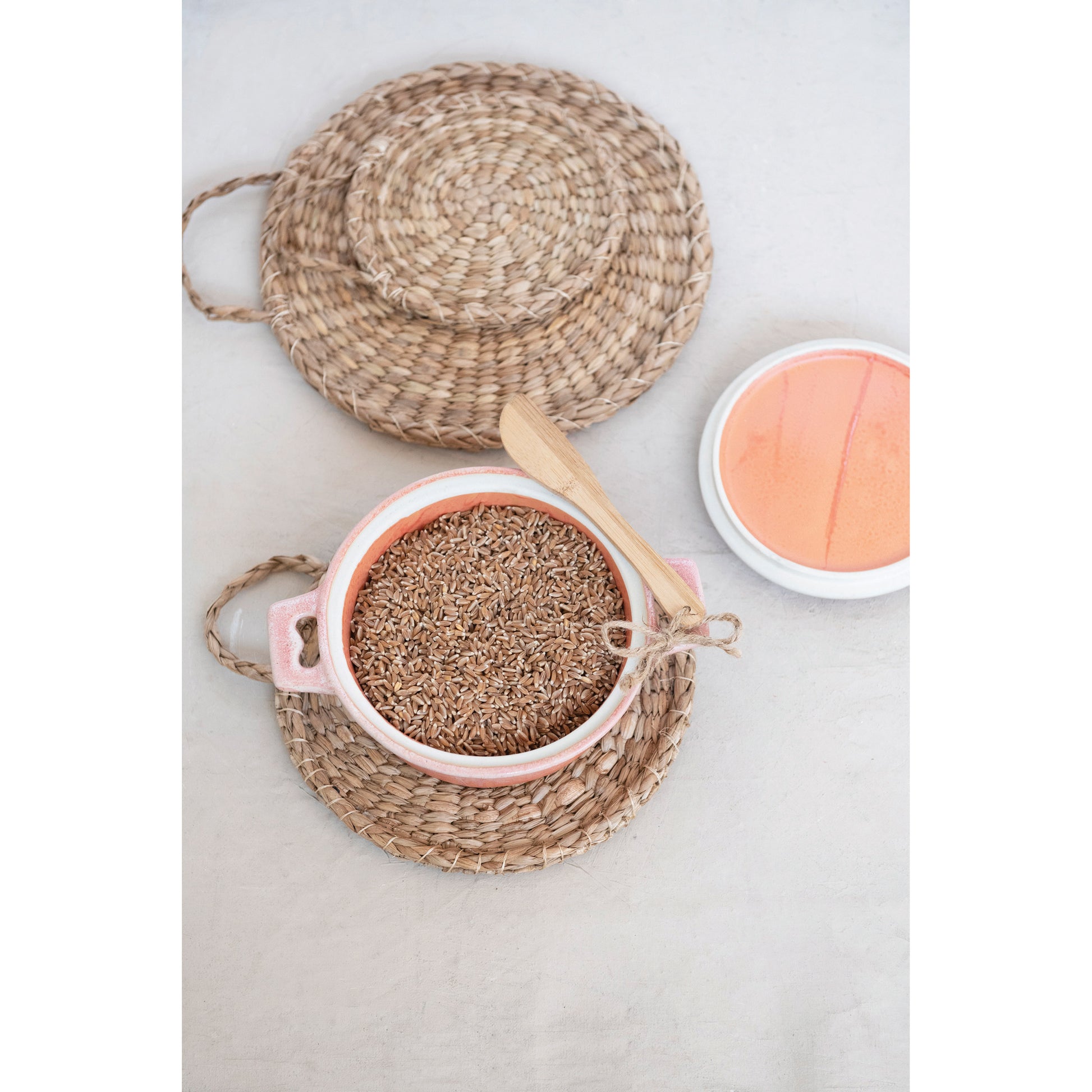 small ceramic baker filled with brown rice set on a woven tray