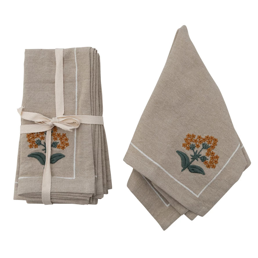 set of cotton floral napkins tied with a ribbon and another napkin draped next to it