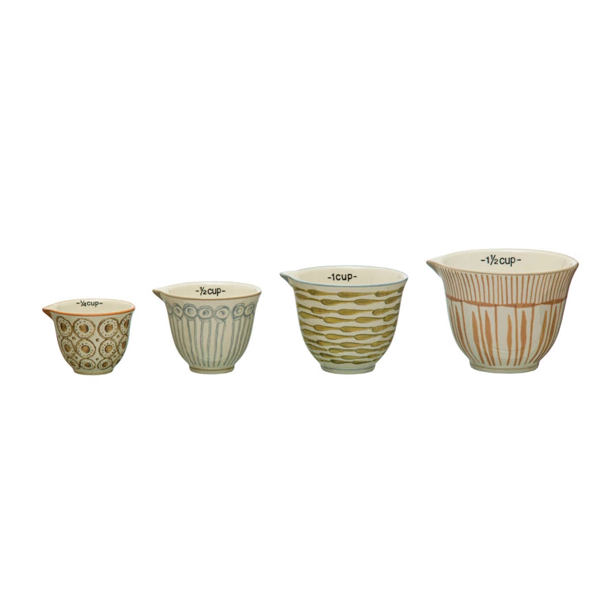all four sizes of hand painted stoneware measuring cups displayed against a white background