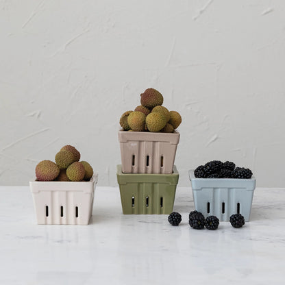 all four colors of textured stoneware berry baskets displayed with fruit and blackberries on white marble surface