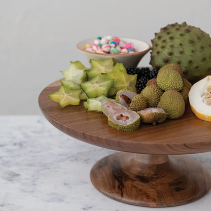 wooden pedestal with assorted fruits arranged on it set on a marble countertop.
