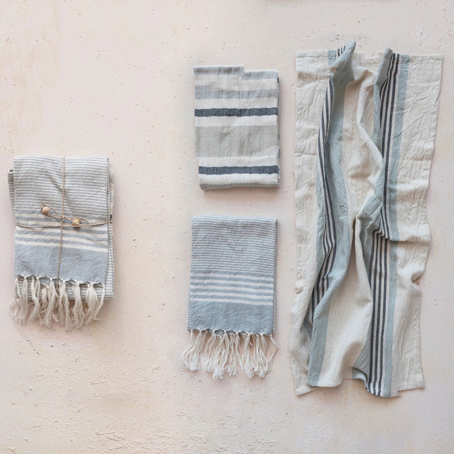 woven cotton tea towels with stripes displayed folded and stacked then open next to the stacked pile on a cream background
