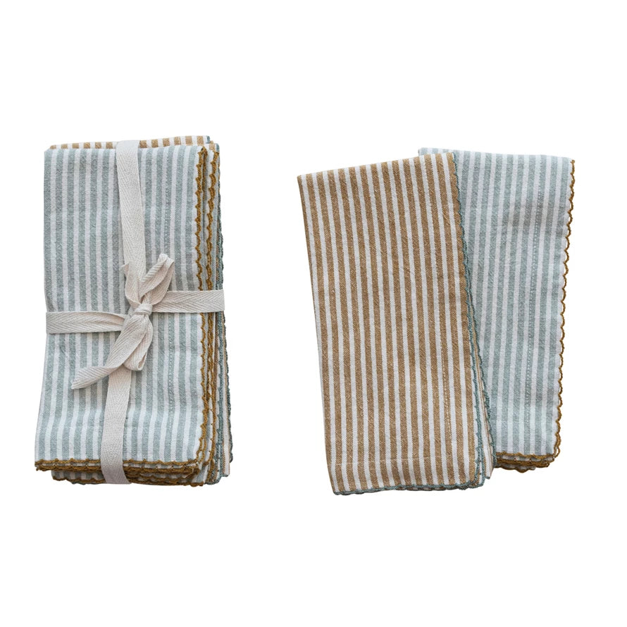 set of napkins folded and tied together with ribbon and 2 other napkins folded and overlapped next to it on a white background.