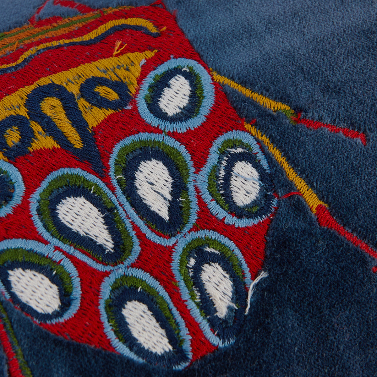 Close-up of navy embroidered pillow with beetle pattern 